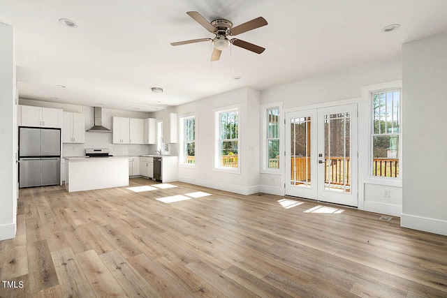 unfurnished living room featuring french doors, ceiling fan, sink, and light hardwood / wood-style flooring