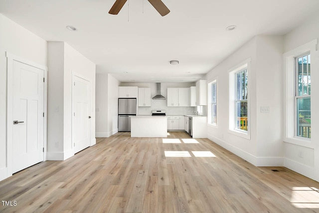 unfurnished living room with ceiling fan, plenty of natural light, light hardwood / wood-style floors, and sink