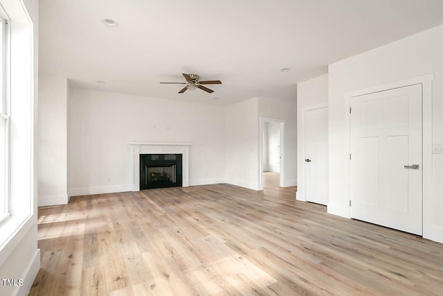 unfurnished living room with ceiling fan, a fireplace, and light hardwood / wood-style flooring