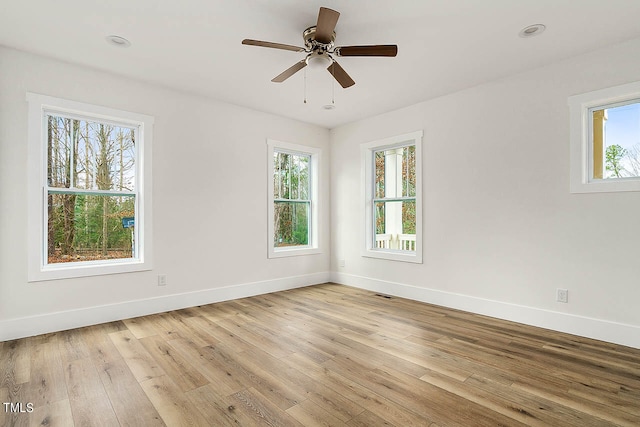 empty room with plenty of natural light, light hardwood / wood-style flooring, and ceiling fan