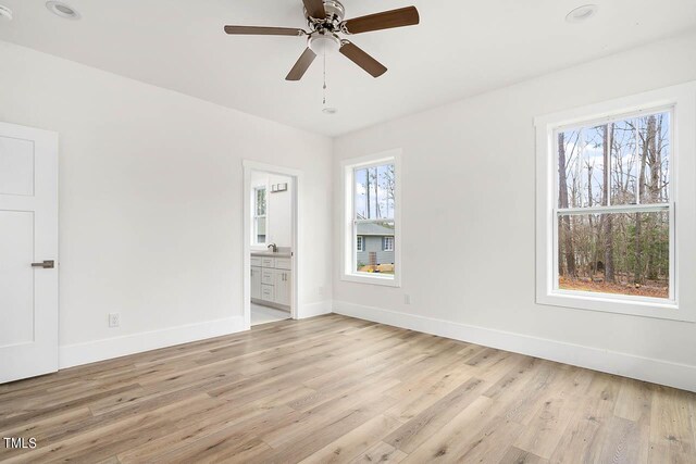 unfurnished bedroom featuring ceiling fan, sink, ensuite bathroom, and light hardwood / wood-style floors