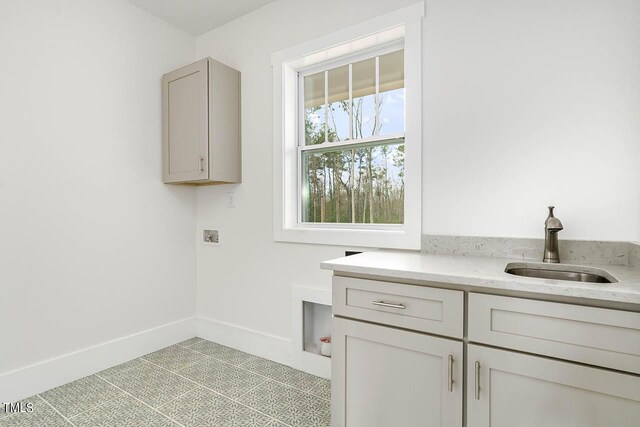 laundry room with light tile patterned floors, hookup for a washing machine, cabinets, and sink