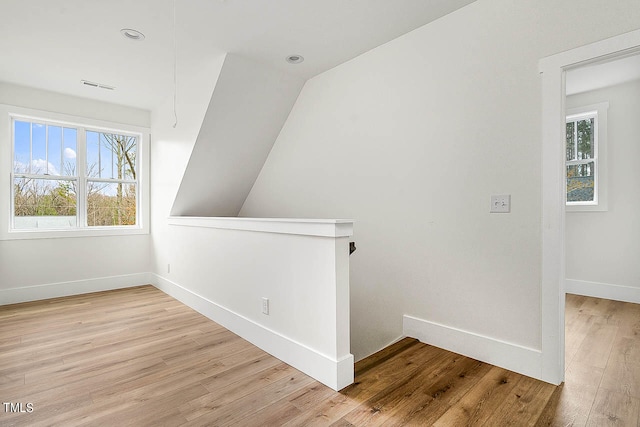 bonus room featuring a healthy amount of sunlight, vaulted ceiling, and light hardwood / wood-style flooring