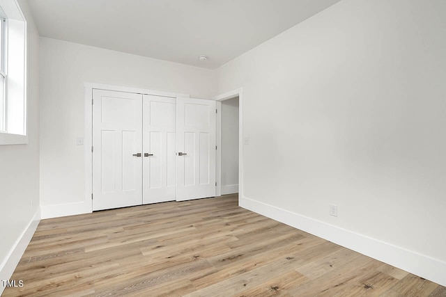 unfurnished bedroom with a closet and light wood-type flooring