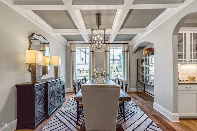 dining room featuring beam ceiling, baseboards, an inviting chandelier, and wood finished floors