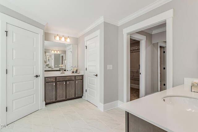 bathroom featuring marble finish floor, baseboards, crown molding, and vanity