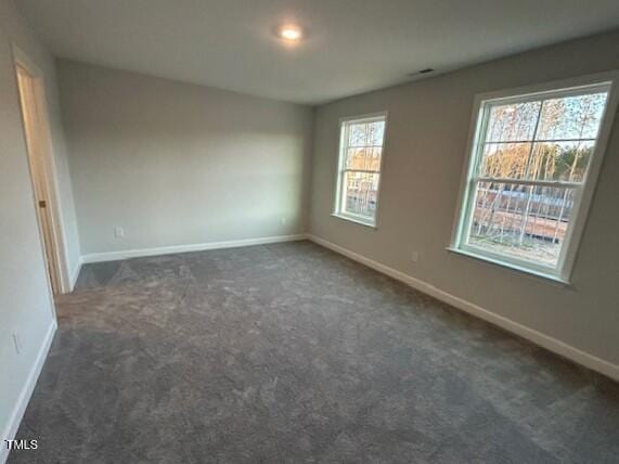 unfurnished room featuring dark carpet and baseboards