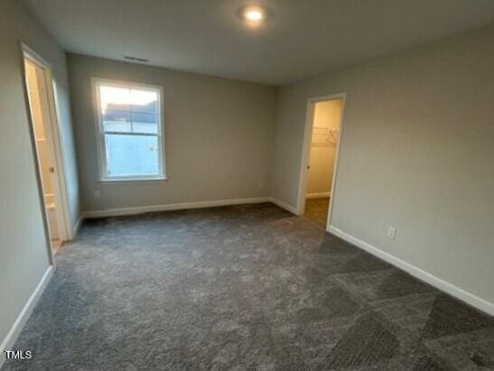 unfurnished bedroom with carpet floors, a spacious closet, and baseboards