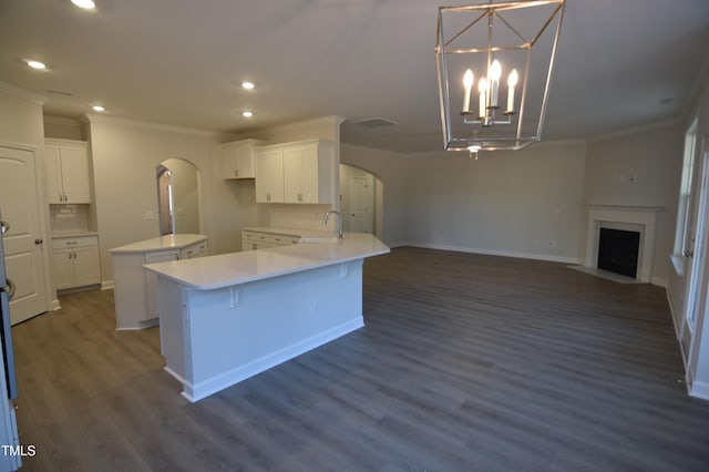 kitchen with arched walkways, an inviting chandelier, a sink, and white cabinets