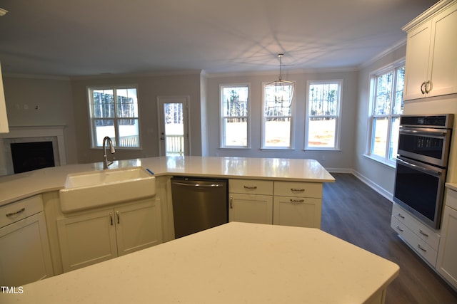 kitchen featuring a fireplace, appliances with stainless steel finishes, a sink, and ornamental molding