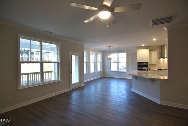 unfurnished living room featuring dark wood-style floors, a sink, visible vents, and crown molding