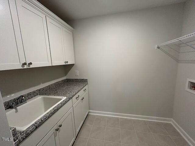 laundry area featuring light tile patterned flooring, hookup for a washing machine, a sink, baseboards, and cabinet space