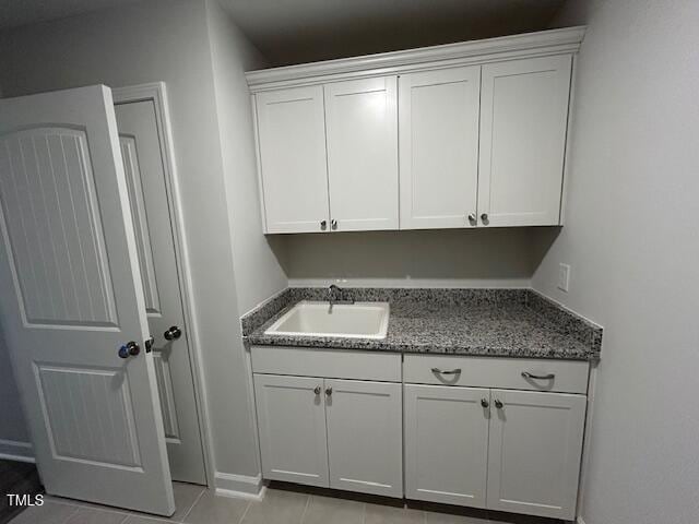 laundry area featuring a sink, baseboards, and light tile patterned floors