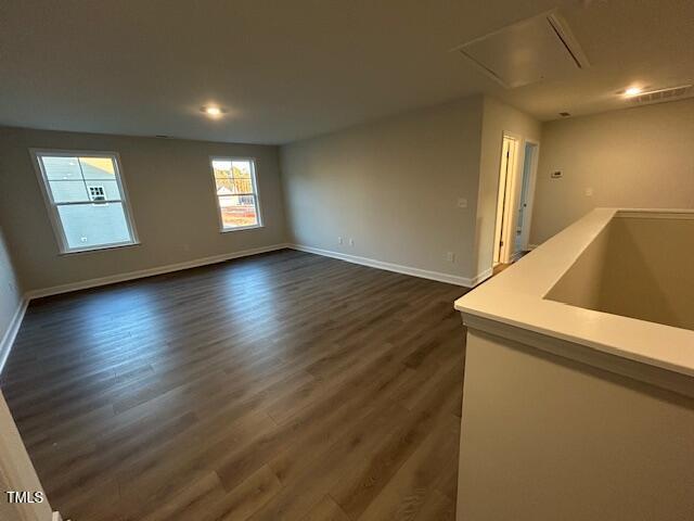 spare room featuring attic access, dark wood finished floors, and baseboards