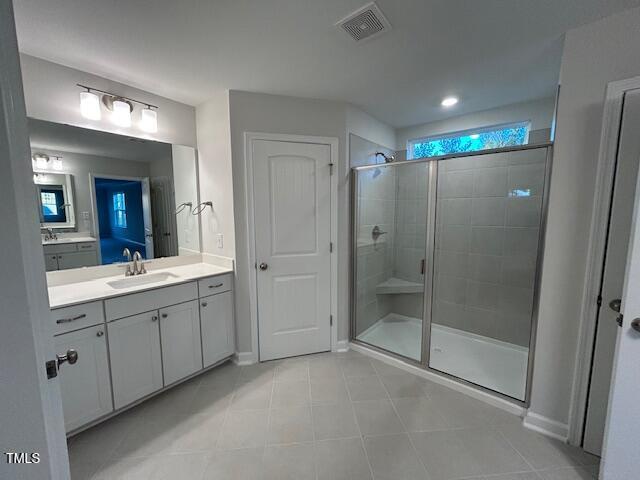 bathroom featuring vanity, a shower stall, and visible vents