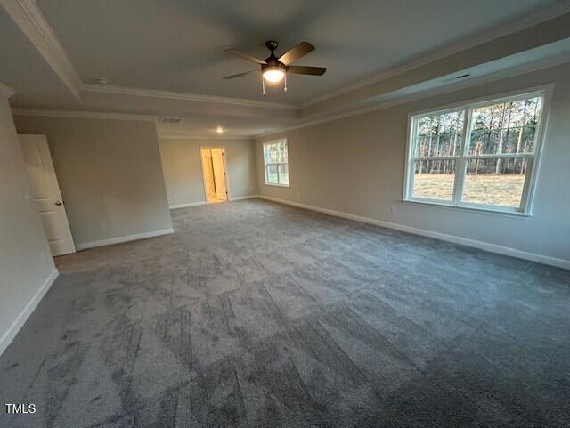 unfurnished room with ornamental molding, a tray ceiling, and baseboards