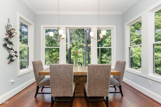 dining room with crown molding, dark wood-type flooring, a healthy amount of sunlight, and an inviting chandelier