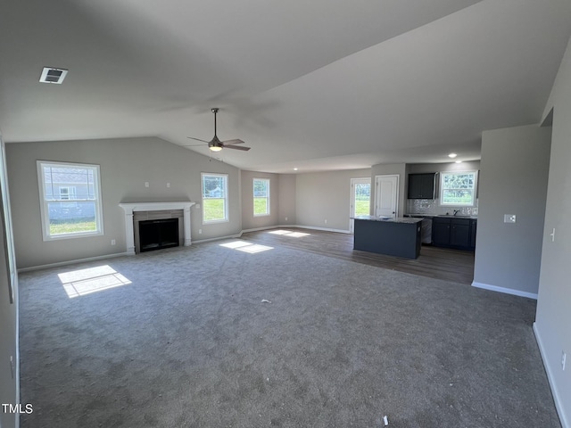 98 Lotus Ave, Smithfield, NC 27577 - unfurnished living room with lofted ceiling, carpet flooring, visible vents, and plenty of natural light
