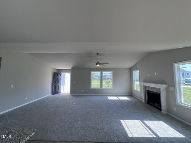 unfurnished living room featuring lofted ceiling, ceiling fan, and carpet flooring