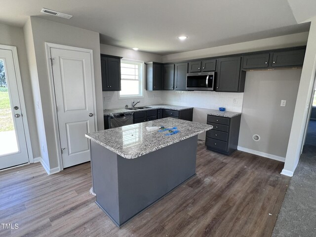 kitchen featuring dishwasher, dark hardwood / wood-style flooring, a center island, sink, and decorative backsplash