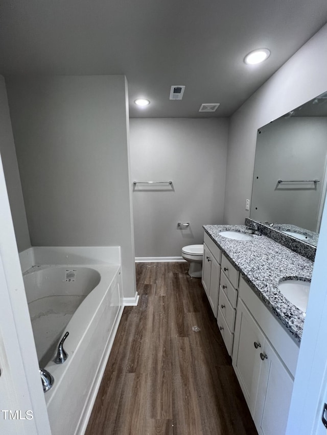 98 Lotus Ave, Smithfield, NC 27577 - full bathroom featuring visible vents, toilet, wood finished floors, a sink, and a garden tub