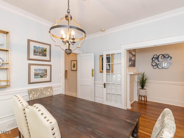 dining area with hardwood / wood-style flooring, a notable chandelier, and ornamental molding