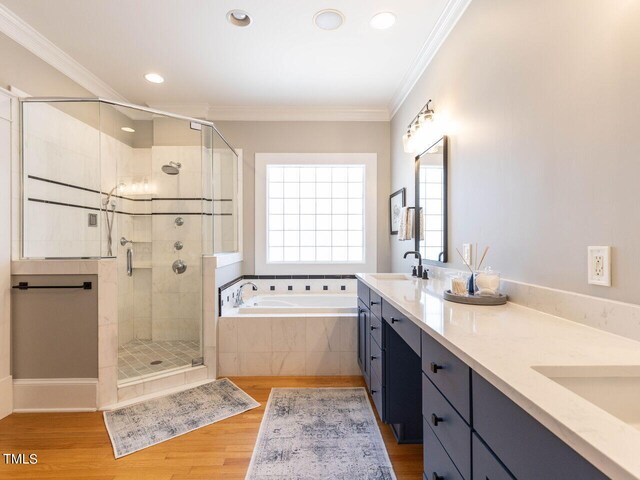 bathroom featuring vanity, ornamental molding, hardwood / wood-style flooring, and shower with separate bathtub