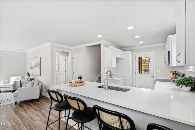 kitchen with sink, dark wood-type flooring, range, kitchen peninsula, and ornamental molding