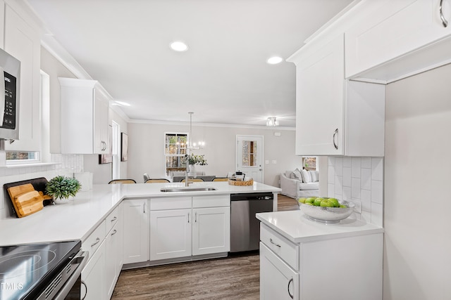 kitchen featuring kitchen peninsula, appliances with stainless steel finishes, decorative backsplash, ornamental molding, and white cabinets