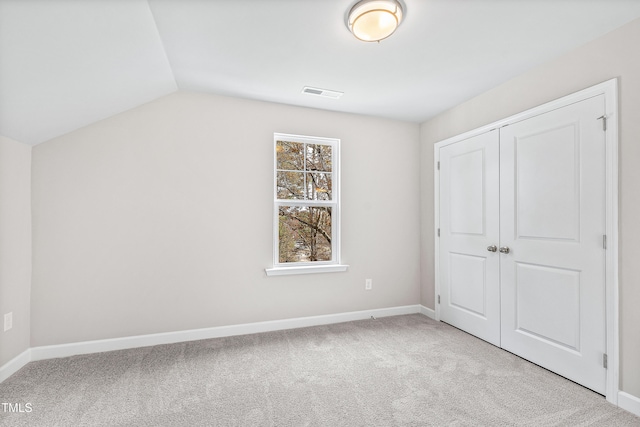 unfurnished bedroom with light colored carpet, vaulted ceiling, and a closet