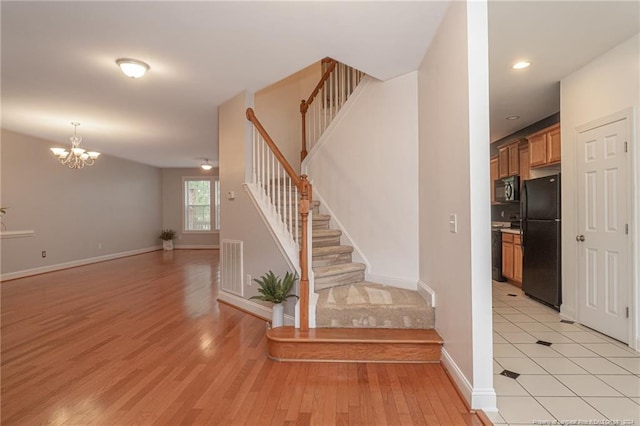 stairway with hardwood / wood-style floors and an inviting chandelier