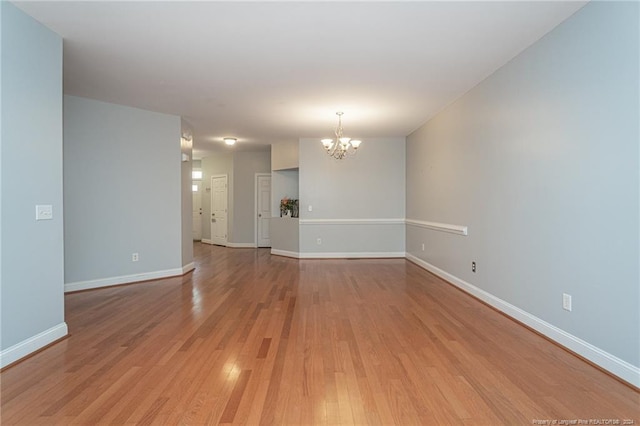 empty room with an inviting chandelier and light hardwood / wood-style flooring