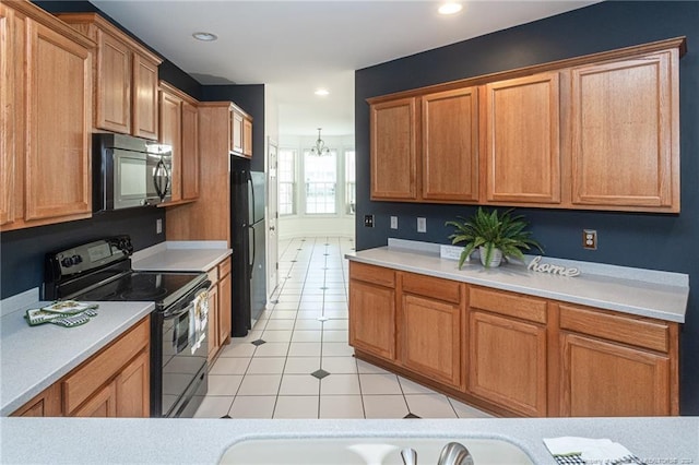 kitchen with stainless steel electric range oven, black fridge, and light tile patterned floors