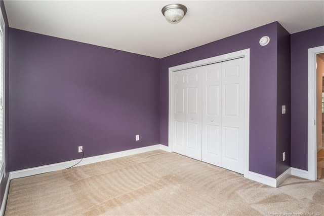 unfurnished bedroom featuring a closet and light carpet