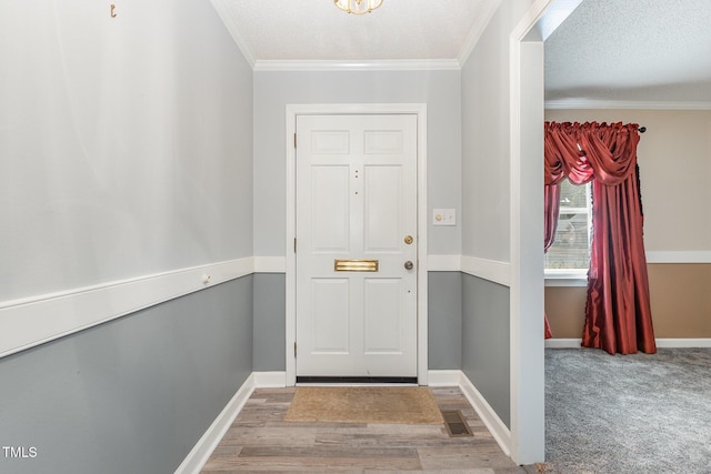 entrance foyer with wood-type flooring, a textured ceiling, and ornamental molding