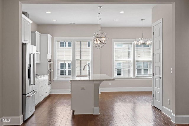 kitchen featuring a kitchen breakfast bar, dark wood-type flooring, a chandelier, a sink, and appliances with stainless steel finishes