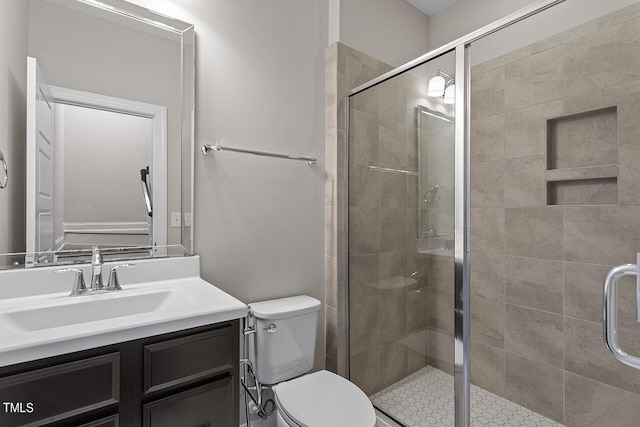 bathroom featuring vanity, toilet, and a shower stall