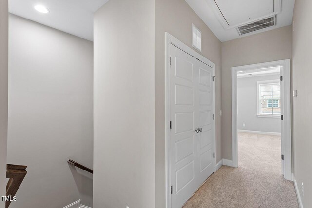hall featuring an upstairs landing, attic access, carpet, baseboards, and visible vents