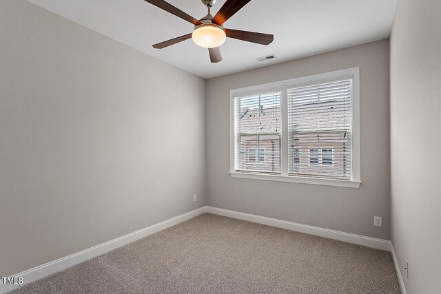 carpeted spare room with baseboards, visible vents, and a ceiling fan