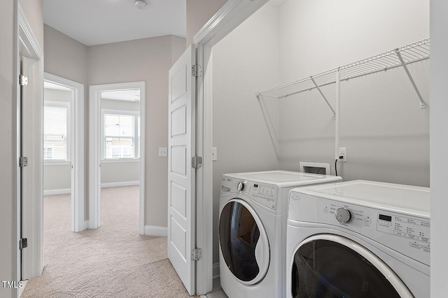laundry area featuring washing machine and clothes dryer, baseboards, laundry area, and light carpet