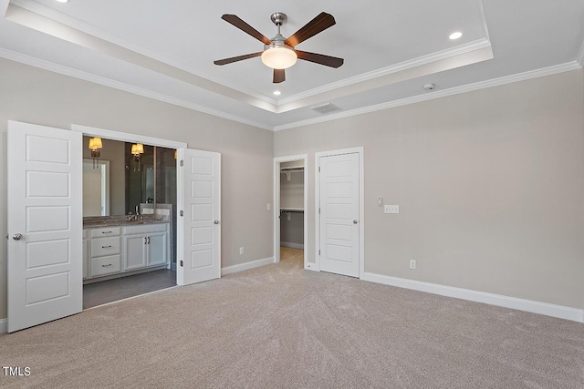 unfurnished bedroom featuring a tray ceiling, carpet floors, baseboards, visible vents, and ornamental molding