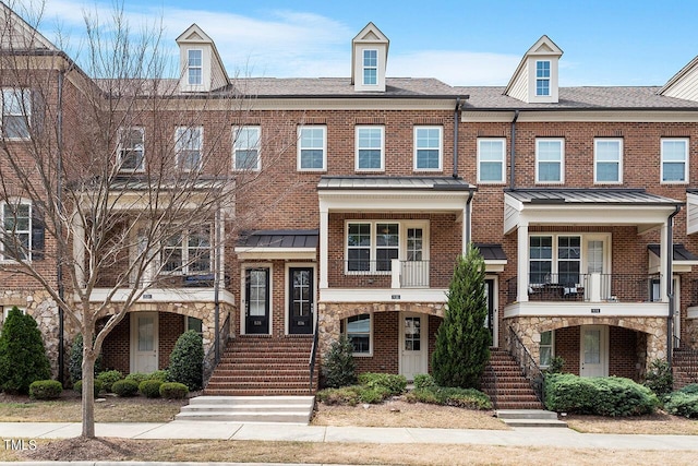 townhome / multi-family property featuring brick siding, a standing seam roof, metal roof, and a shingled roof