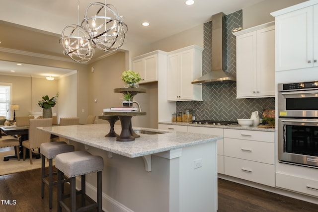 kitchen with decorative backsplash, dark wood-style floors, white cabinets, appliances with stainless steel finishes, and wall chimney exhaust hood