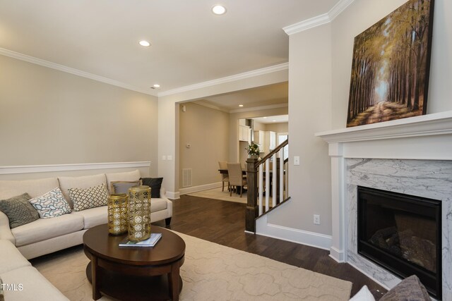 living room featuring baseboards, visible vents, ornamental molding, and wood finished floors