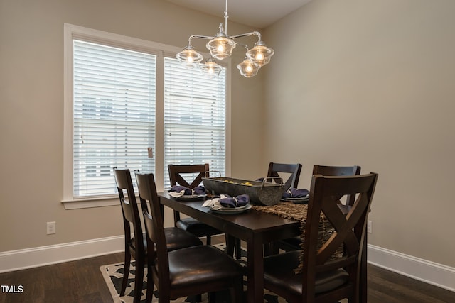 dining room featuring dark wood-style flooring, a notable chandelier, and baseboards