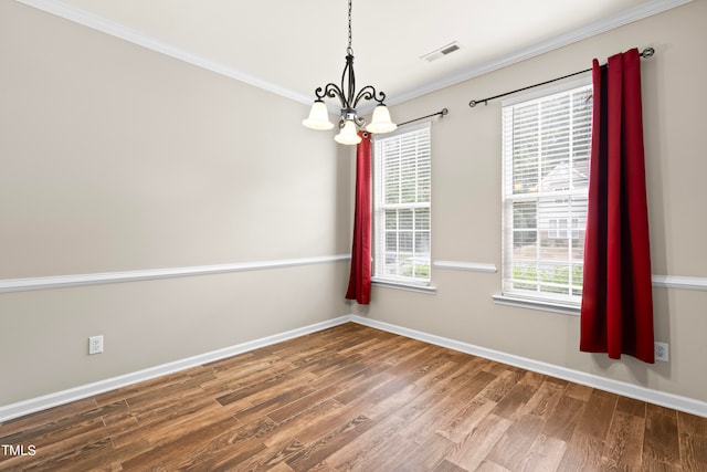 empty room featuring crown molding, a notable chandelier, and wood-type flooring