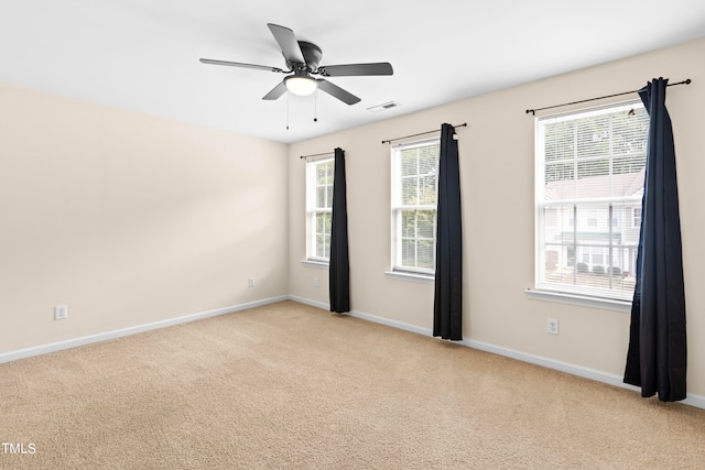 carpeted empty room with a wealth of natural light and ceiling fan