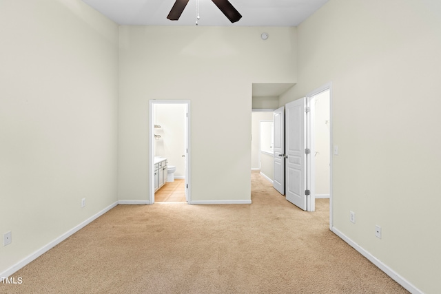 unfurnished bedroom with connected bathroom, light carpet, and ceiling fan