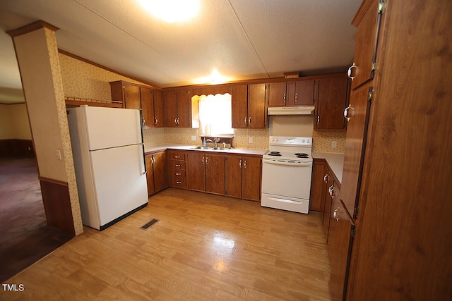 kitchen with a textured ceiling, white appliances, light hardwood / wood-style floors, sink, and lofted ceiling