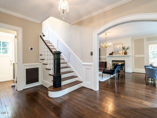 stairs featuring an inviting chandelier, ornamental molding, and hardwood / wood-style floors